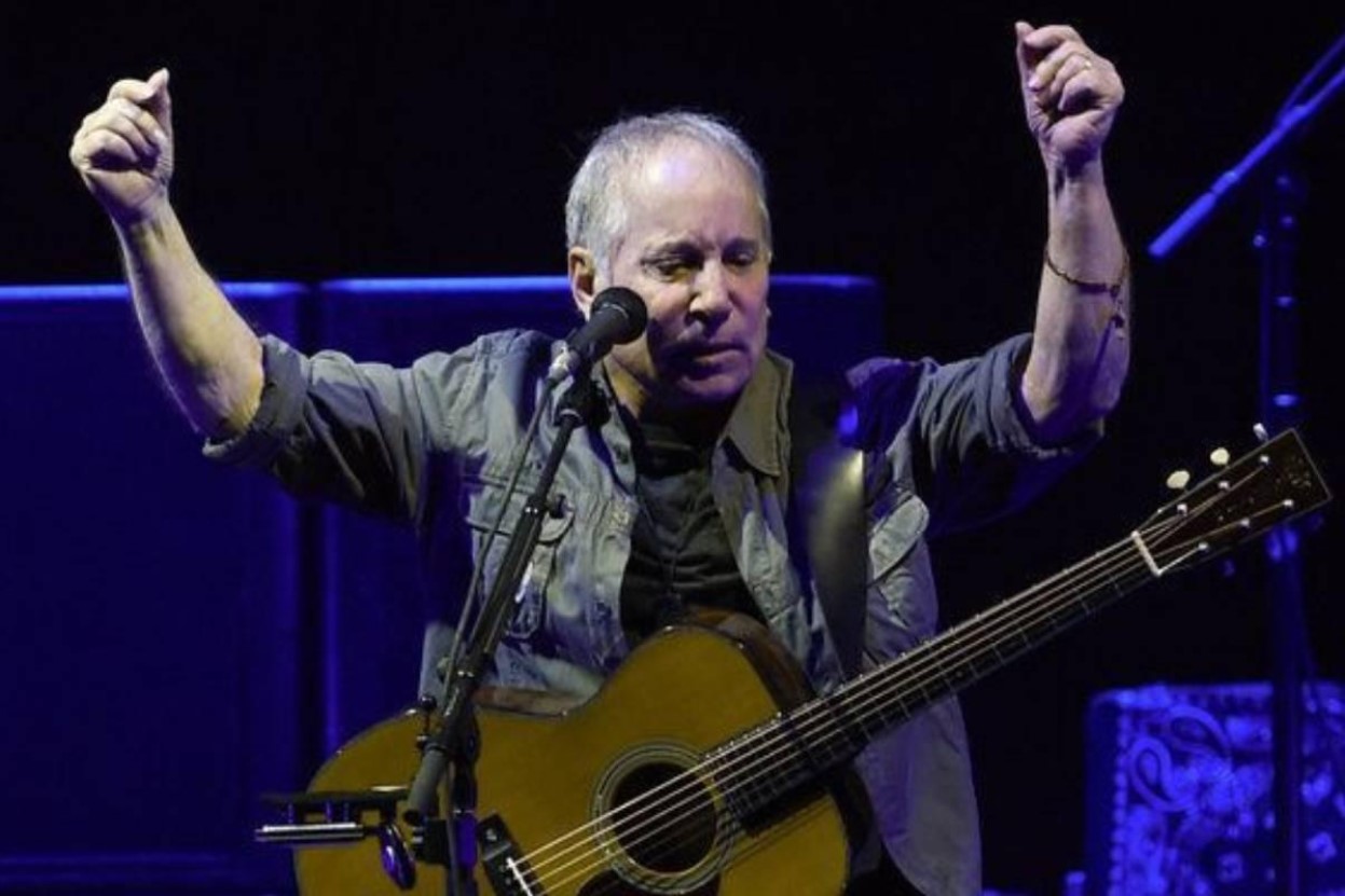 Paul Simon With Hands Up on Stage