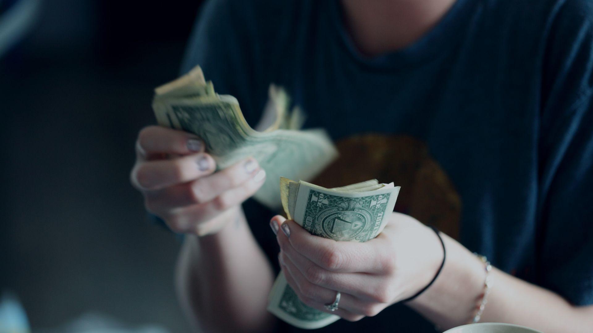 A person is counting dollar bills