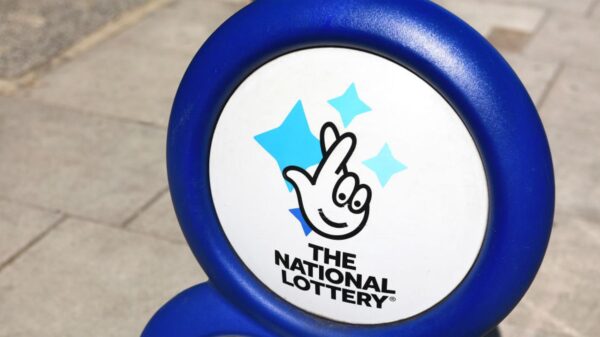 Plastic sign of the United Kingdom national lottery sits outside of a small shop