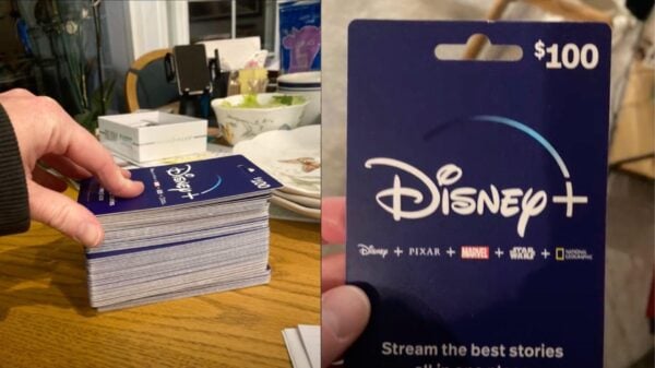 A photograph displaying a person's hand holding a stack of blue Disney+ gift cards, each valued at $100, with the logo and tagline "Stream the best stories" visible on one card held at the forefront. On the right hand side of the image is a close-up view of the gift card