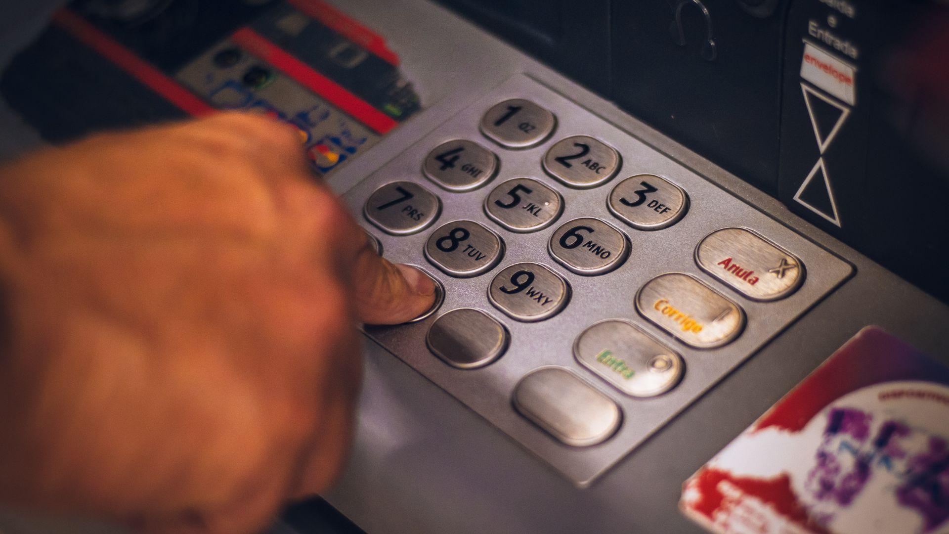 A close-up image of a person's hand pressing the buttons on an ATM keypad