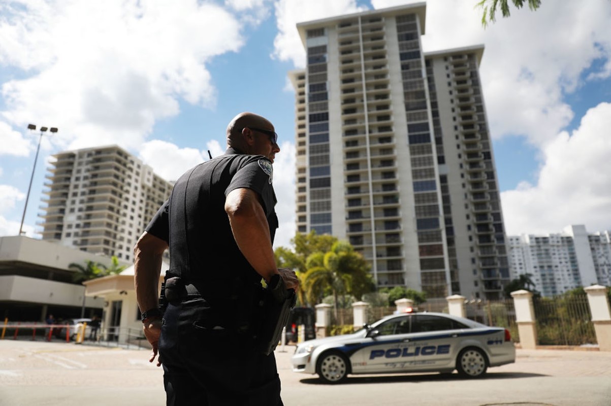 An Aventura City police officer stands across the street from the condo building
