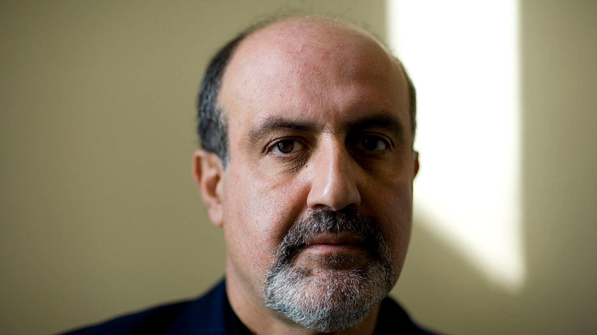 Nassim Nicholas Taleb with a balding head and a salt-and-pepper beard is looking directly at the camera with a serious expression