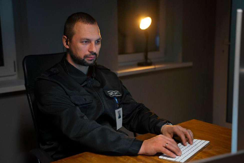 Police officer sits at a computer in a precinct at night