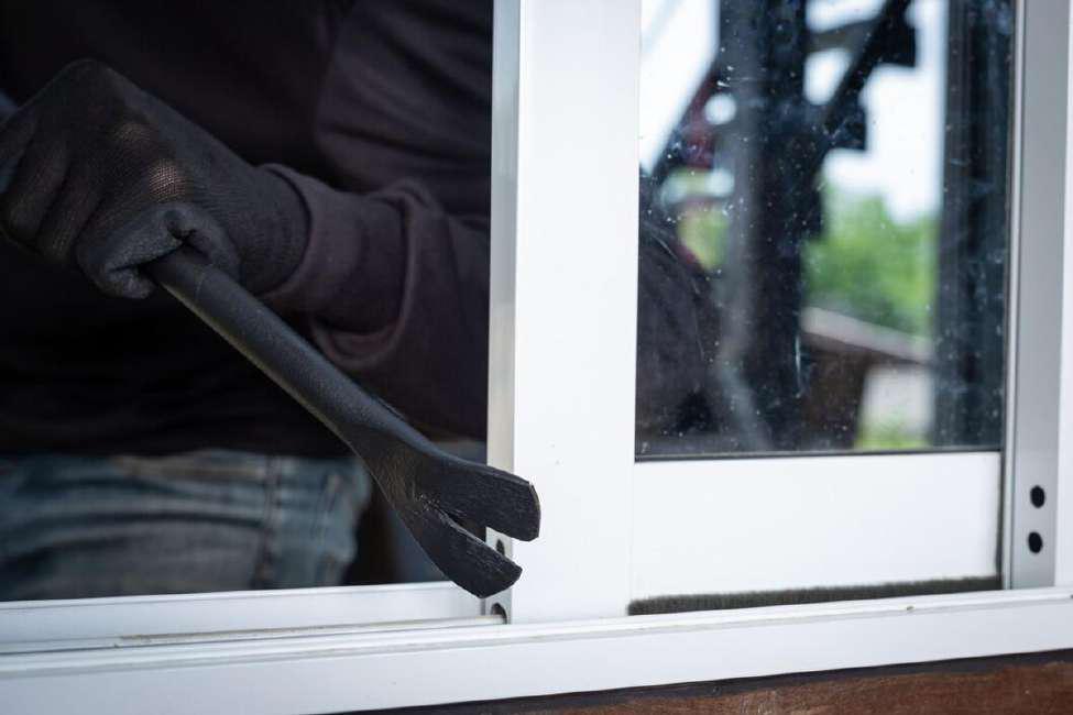 Burglar breaking into a house with a crowbar through the window
