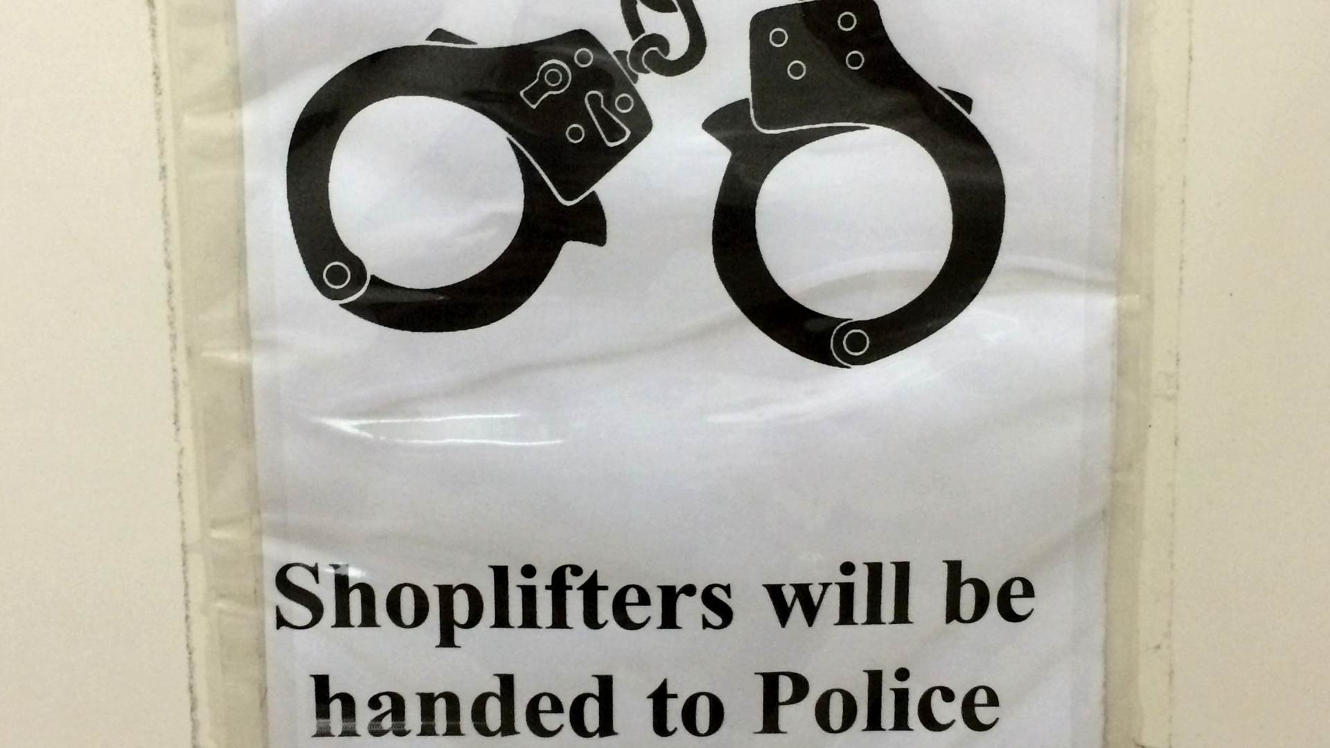 A shop lifting sign featuring a pair of handcuffs.