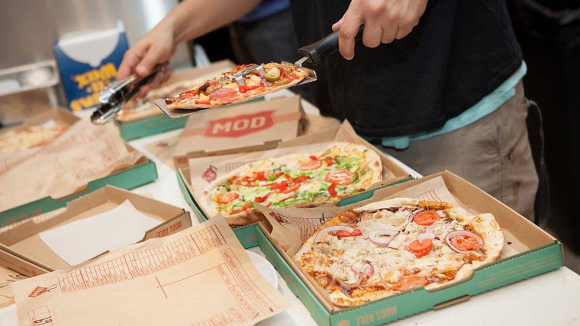 Three Pizzas Being Packaged Into Boxes